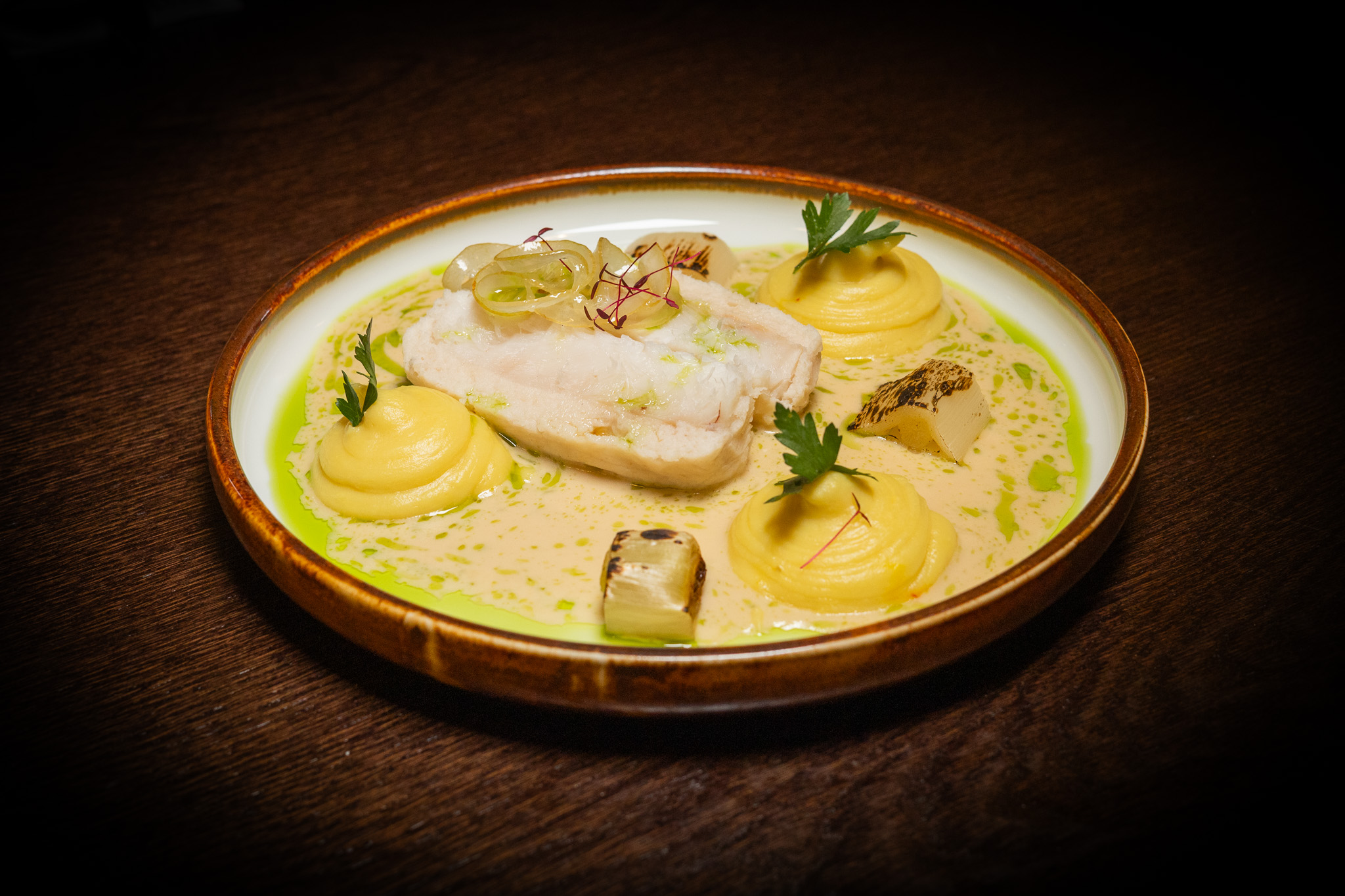 MERLUZZO IN CAMICIA, SALSA DI PESCE ALLA PANNA, PORRO ARROSTITO, LIMONE MARINATO, PUREA DI PATATE ALLO ZAFFERANO